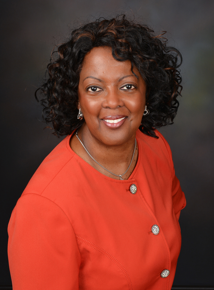 A woman in an orange shirt is smiling for the camera.