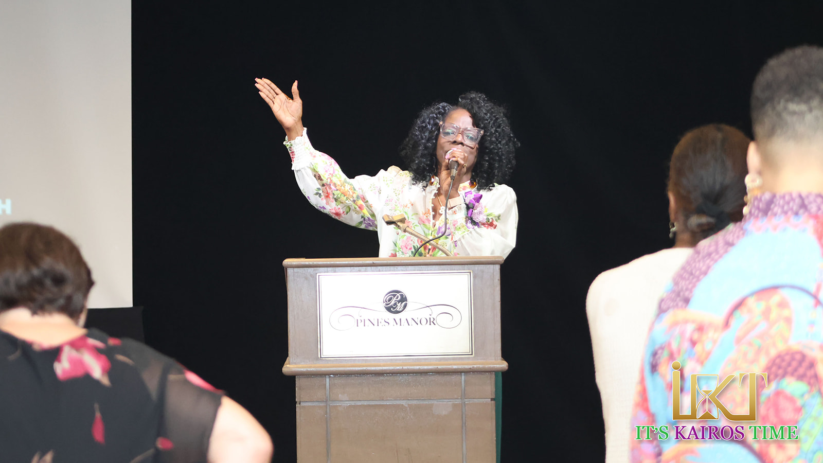 Woman speaker gesturing behind podium to audience