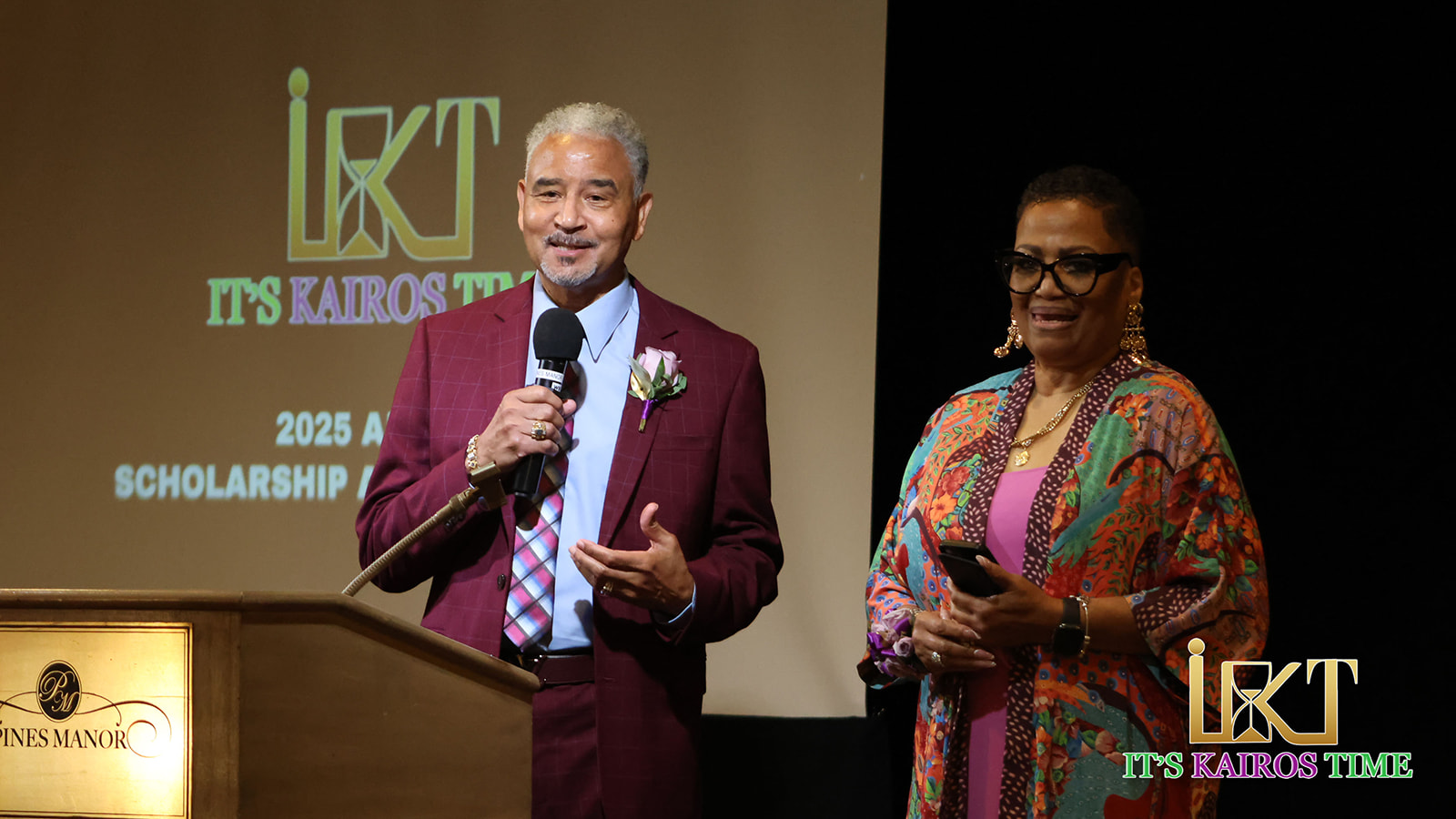 Two presenters on stage with Kairos backdrop