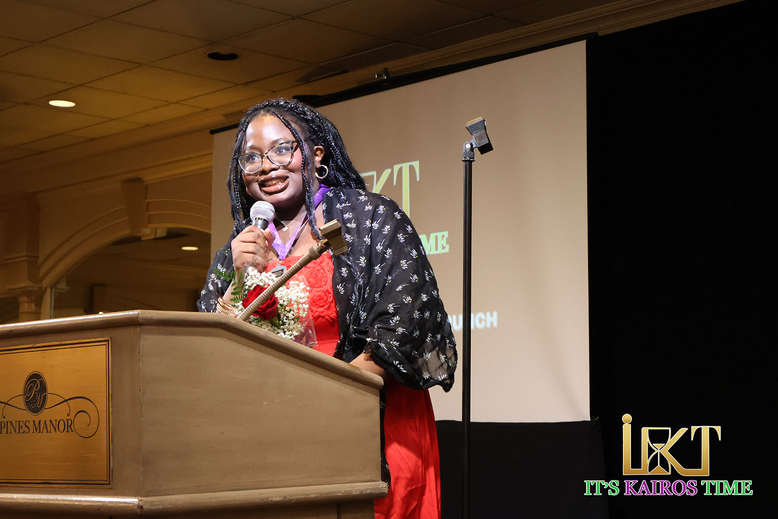 Smiling speaker in red dress holding microphone