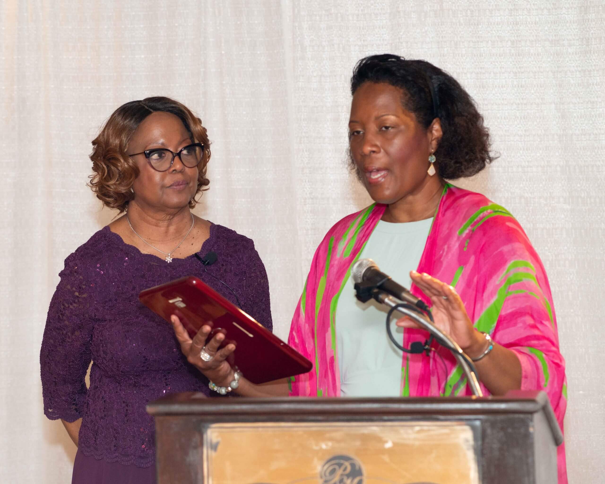 Two women speaking at a podium during an event.